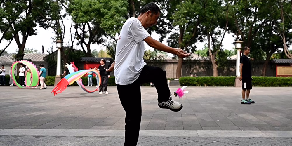 Auf dem Bild sieht man ein Kind mit hellem T-Shirt und dunkler Hose von der Seite, das Federfußball spielt.