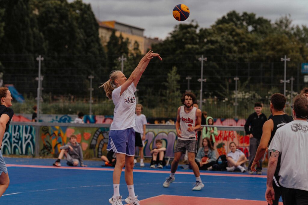 Auf dem Bild ist eine Basketballerin zu sehen, die gerade auf einen Basketballkorb wirft.