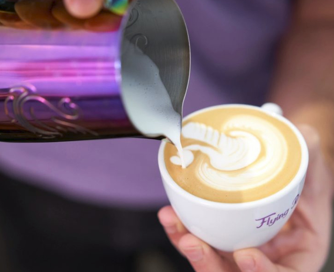 Milchschaum wird in eine Tasse gegossen